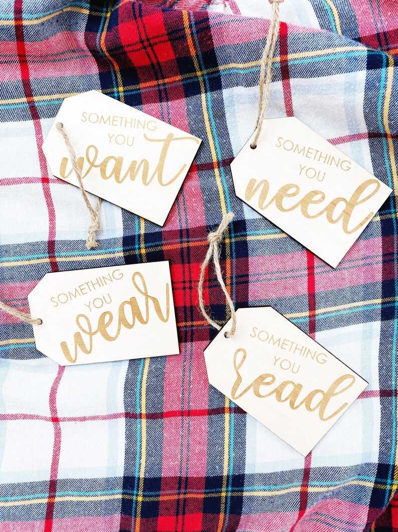 May include: Four wooden gift tags with twine attached. Each tag has a different phrase written on it: "Something you want", "Something you need", "Something you wear", and "Something you read".