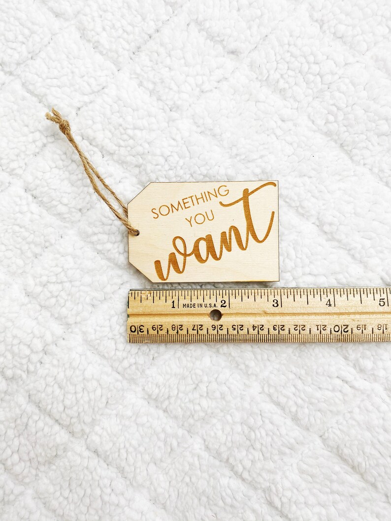 May include: A wooden tag with the text "SOMETHING YOU WANT" written in a cursive font. The tag is tied with a brown twine string.
