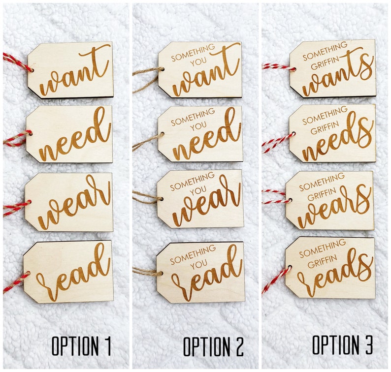 May include: Three sets of four wooden gift tags with red and white twine. Each set has the words "want", "need", "wear", and "read" with the text "Something you" or "Something Griffin" above the words.