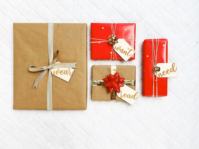 May include: Four wrapped gifts with gold ribbon and tags. The tags have the words "wear", "want", "read", and "need" written on them.