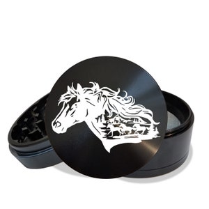 May include: Black metal grinder with a white silhouette of a horse's head and a forest scene. The grinder has a removable top and a screen.