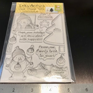 May include: Clear stamp set with a Christmas theme. The set includes a bird with a hat and ornament, a Christmas tree, and the text "Merry Christmas", "Hope your holidays are decorated with happiness!" and "From our family tree to yours".