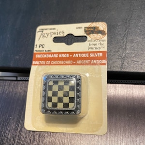 May include: A silver checkered knob with a black and white checkered design. The knob is packaged on a card with the text "7gypsies" and "Checkboard Knob - Antique Silver".