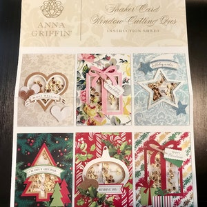 May include: A sheet of instructions for shaker card window cutting dies. The sheet shows six different shaker card designs with various themes, including birthday, get well, and Christmas. Each design features a window cut-out with a shaker element filled with sequins.