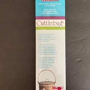 May include: A Cuttlebug Fringe Flower Kit with two cutting dies. The kit includes a sample flower made with the dies, a metal bucket with a flower embellishment, and a bag of blue beads. The packaging is blue and white with the Cuttlebug logo.