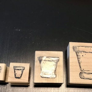 May include: Four wooden stamps with different sizes of plant pots, each with a black and white line drawing of a pot.