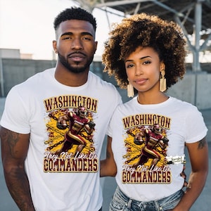 May include: Two people wearing white t-shirts with a Washington Commanders football design. The design features a football player in burgundy and gold, the word "WASHINGTON" above, and "They Not Like Us COMMANDERS" below.