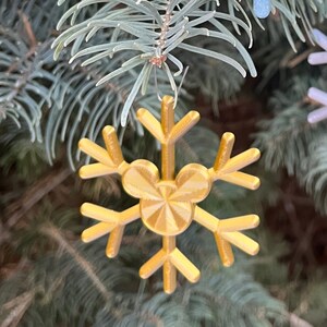May include: Three snowflake ornaments with a Mickey Mouse silhouette in the center. The snowflakes are blue, gold, and silver with glitter.