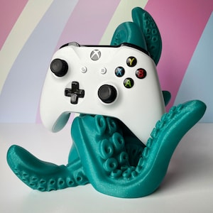 May include: A teal blue 3D printed octopus holding a white Xbox controller. The controller has black buttons and a black D-pad.