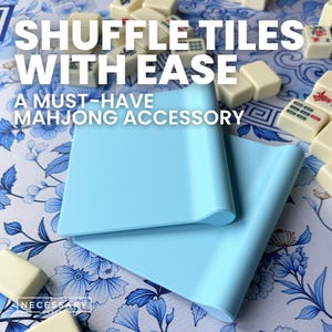 May include: A light blue Mahjong tile shuffler with the text "Shuffle Tiles With Ease" and "A Must-Have Mahjong Accessory". The shuffler is on a floral patterned surface with Mahjong tiles in the background.