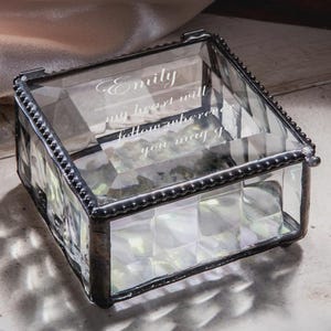May include: A clear glass keepsake box with a hinged lid and a decorative beaded border. The box features a geometric pattern on the sides and the inscription "Emily my heart will follow where you may go."