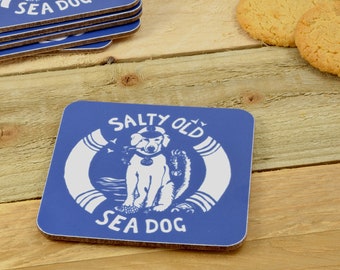 May include: Blue square coaster with a white illustration of a dog wearing a captain's hat and a life preserver. The text "Salty Old Sea Dog" is written in a white circle around the dog.