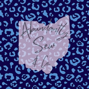 May include: A blue and white leopard print background with a white outline of the state of Ohio. The text "Abundantly Sew & Co." is written in cursive inside the outline.