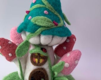 May include: A felt mushroom house with a green roof, pink and white mushrooms, and a brown door. The house is decorated with green vines and pink flowers.