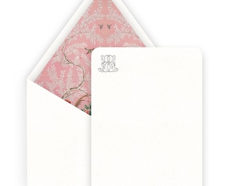 May include: A white card with a pink floral pattern on the back. The front of the card has a monogram with the letters "M.O.F." in a decorative font.