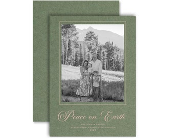 Op de afbeelding: Een groene kerstkaart met een familiefoto in een crèmekleurige lijst. De kaart leest "Peace on Earth" in een cursief lettertype, met de namen van de familie en het jaar 2023 eronder. De kaart heeft een rechthoekige vorm.