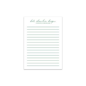 Puede incluir: Un bloc de notas rectangular blanco con líneas horizontales de color verde oscuro. En la parte superior, el texto "kate chambers designs" en fuente cursiva, seguido del sitio "www.katechambers.com" y "@katechambersdesigns".