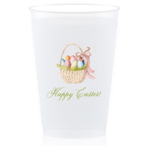 Op de afbeelding: Een doorzichtige plastic beker met een aquarel illustratie van een mandje gevuld met kleurrijke paaseieren en een roze strik. De woorden "Happy Easter!" staan eronder in groene letters.