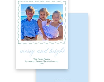 May include: A holiday card featuring a family photo within a decorative green border. The card reads "merry and bright" with the family name and year. The card has a light blue background and a photo of three children.