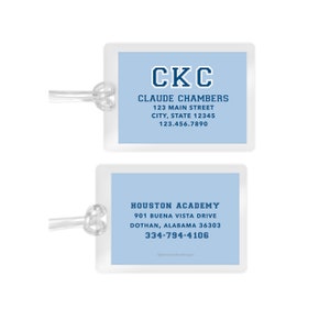 May include: Two blue luggage tags with white text. The top tag says "CKC CLAUDE CHAMBERS 123 MAIN STREET CITY, STATE 12345 123.456.7890". The bottom tag says "HOUSTON ACADEMY 901 BUENA VISTA DRIVE DOTHAN, ALABAMA 36303 334-794-4106".