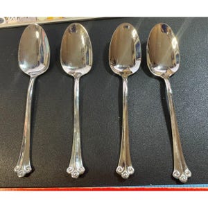 Può includere: Quattro cucchiai d'argento con manici decorati. I cucchiai hanno una ciotola arrotondata e un manico lungo e sottile con un design decorativo all'estremità.