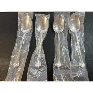 Può includere: Quattro cucchiai d'argento confezionati singolarmente in plastica. I cucchiai presentano un design decorato e ornato all'estremità del manico.