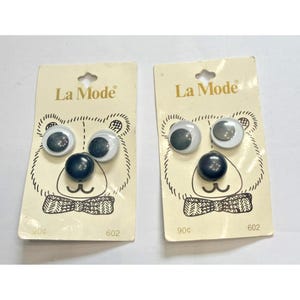 May include: Two La Mode brand button sets on cream-colored cards featuring a bear illustration. Each card includes two white buttons with dark centers and one solid dark blue button, arranged to resemble a bear face. The text 602 is printed.