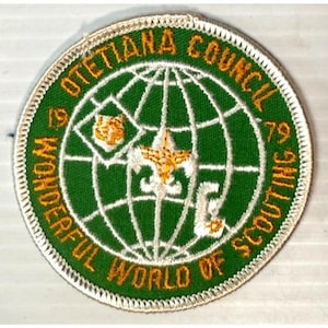 May include: A round patch with a green base and white edging. It displays a globe design with the words "OTETIANA COUNCIL" and "WONDERFUL WORLD OF SCOUTING" in gold. The year "79" is also included in the design.