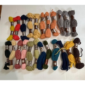 May include: A collection of colorful embroidery floss skeins in various shades, including yellow, red, blue, green, and orange. Each skein is neatly wrapped and labeled, perfect for craft projects.