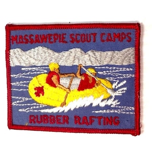 May include: Embroidered patch with a blue background and red border. The patch features the text "MASSAWEPIE SCOUT CAMPS" and "RUBBER RAFTING" in red. A yellow raft with two figures in red vests is depicted on a blue and white water scene.