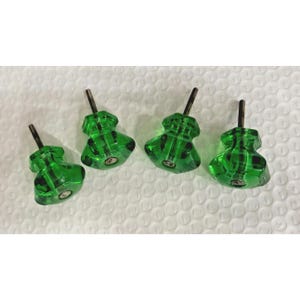 Puede incluir: Cuatro pomos de armario de vidrio verde con un diseño facetado. Cada pomo tiene un tornillo metálico para la instalación. Los pomos son de color verde vibrante y parecen estar hechos de vidrio transparente.