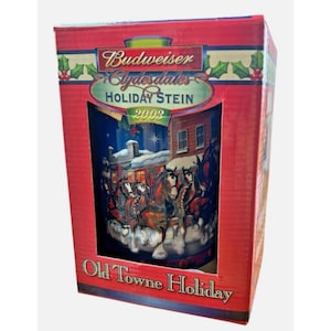 Può includere: Un Budweiser Clydesdales Holiday Stein 2003 nella sua scatola originale. La scatola è rossa con accenti di agrifoglio verde. Lo stein presenta una scena invernale con cavalli e un edificio. Le parole "Old Towne Holiday" sono stampate.