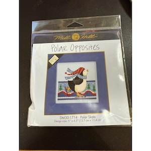 May include: A cross-stitch kit titled "Polar Opposites" featuring a penguin ice skating. The penguin wears a red and white hat and scarf. The design size is 5" x 4.5" (12.7 cm x 11.4 cm).