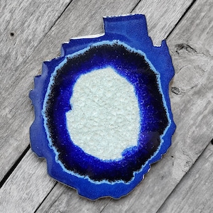 May include: A blue and white agate coaster with a white center and a blue and black outer ring.