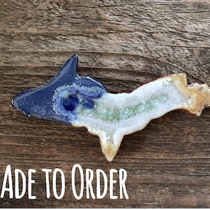 May include: A ceramic sculpture of the Upper Peninsula of Michigan, with a blue and white glaze on one side and a brown and white glaze on the other side. The sculpture is made to order.
