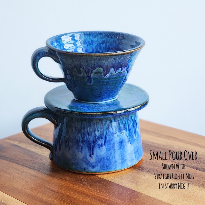 May include: A two-piece ceramic pour-over coffee set in a deep blue glaze with a drippy, textured finish. The set includes a cone-shaped pour-over and a straight-sided mug. The text "SMALL POUR OVER" is visible in the image.