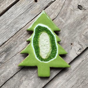 May include: A green ceramic Christmas tree ornament with a white and green crackle glaze design.
