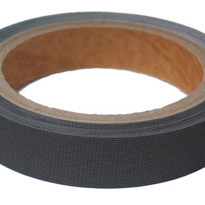 May include: A roll of black fabric tape with a textured surface. The tape is wrapped around a cardboard core. The tape appears to be approximately 1 inch wide.