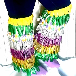 May include: A pair of leg warmers with a layered design featuring green, yellow, purple, and white fringe. The leg warmers are made of a mesh fabric with a diamond pattern.