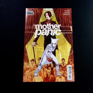 May include: A comic book cover for "Mother Panic" features a costumed character in white and red, set against a backdrop of a figure in a dark suit and a crowd. The title is in large white letters. The Young Animal logo is in the upper left corner.