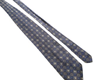 Puede incluir: Una corbata azul con un diseño geométrico blanco y dorado.