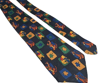 Könnte beinhalten: Eine dunkelblaue Seidenkrawatte mit einem sich wiederholenden Muster aus Winnie Puuh und Tigger Figuren, grünen Kleeblättern und orangefarbenen und gelben Quadraten.
