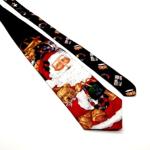 Może przedstawiać: Czerwono-biało-czarny krawat świąteczny z motywem Świętego Mikołaja i pluszowego misia. Krawat ma czarną stronę odwrotną z powtarzającym się wzorem bębnów i cukierków.