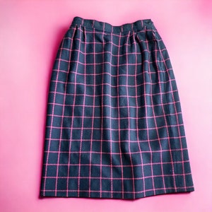 May include: A black skirt with a pink checked pattern. The skirt has a button fastening at the waist.