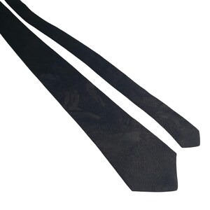 May include: A black tie with a subtle floral pattern. The tie is made of a textured fabric and is angled across a white background. The tie's design is simple and elegant, suitable for formal occasions.