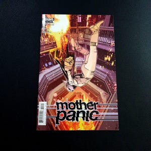 May include: A comic book cover featuring a figure in a white and beige suit falling headfirst. The title "mother panic" is displayed in large, stylized letters. The background shows a detailed interior with a fiery explosion.