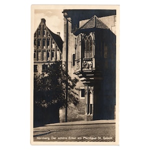May include: Vintage black and white postcard featuring a detailed architectural view of a building with a prominent bay window. The postcard shows a cobblestone street and the text "Nürnberg, Der schöne Erker am Pfarrhaus St. Sebald."