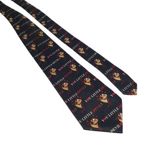 May include: A black necktie featuring a repeating pattern of the Tasmanian Devil cartoon character, hearts, and the phrase "YOU LITTLE DEVIL!" in white and red. The tie is a classic accessory.