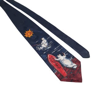 Peut inclure: Une cravate en soie bleue avec un logo Coca-Cola rouge et blanc et un ours polaire sur une planche de surf. La cravate a un soleil blanc et un deuxième ours polaire en arrière-plan.
