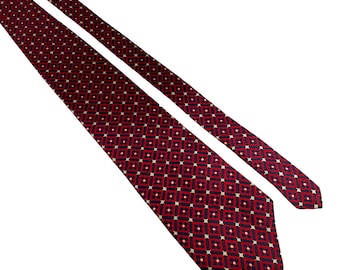 May include: A red tie with a repeating geometric pattern of small squares and white dots. The tie is angled across a white background, showcasing its design and texture. The pattern is a classic design for formal wear.
